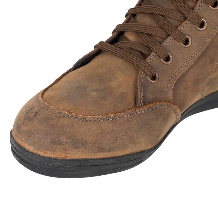 A close-up of a brown suede boot with laces against a white background.