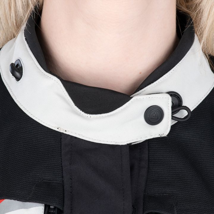 Close-up image of a person's neck wearing a black and white garment with a high collar and a button fastening detail.