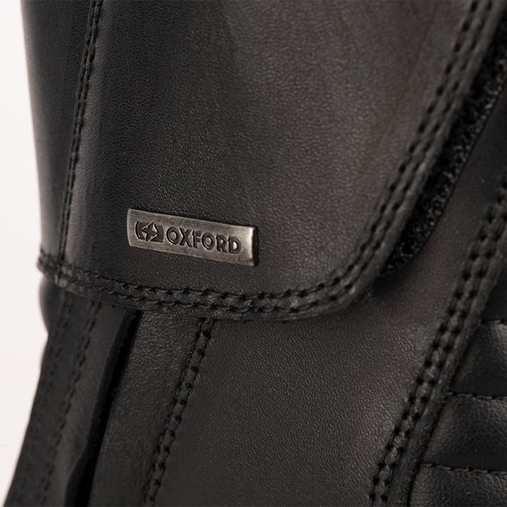 Close-up of a black leather boot with an embossed 'OXFORD' brand logo on a small rectangular patch.