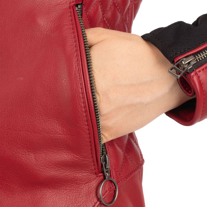 A person's arm inserted into the pocket of a red leather jacket with a visible zipper and pull ring.