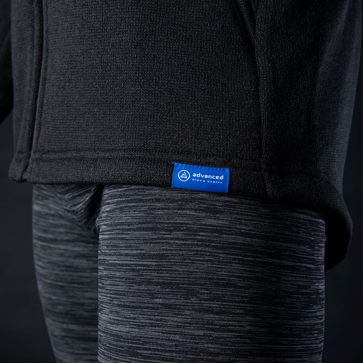 A close-up image of a dark grey hoodie and heather grey leggings with a small blue label reading "advanced" on the hoodie's hem.