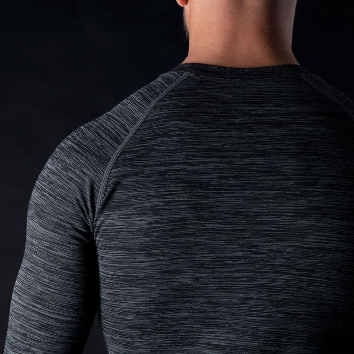 Rear view of a person wearing a fitted, dark heathered gray long-sleeve athletic shirt against a black background.