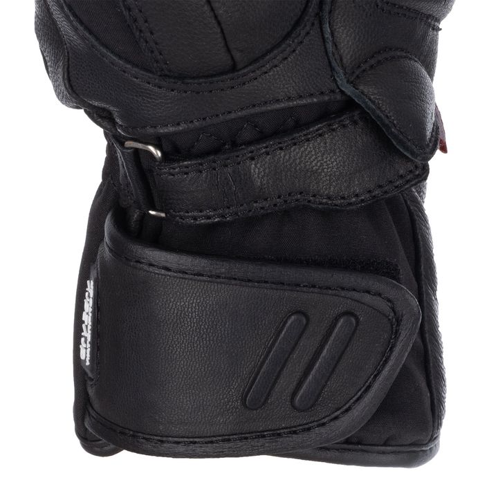 A close-up of a black motorcycle glove featuring protective padding and a Velcro strap.