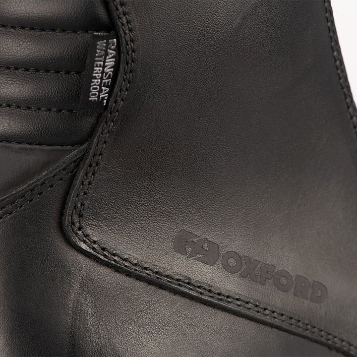 Close-up of a black leather shoe with the "OXFORD" brand debossed on it and a "WATERPROOF" label stitched on the side seam.