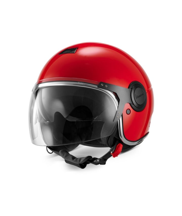 A red motorcycle helmet with a clear visor, black padding, integrated communication system on the left side, and brand logo on the right side, against a white background.