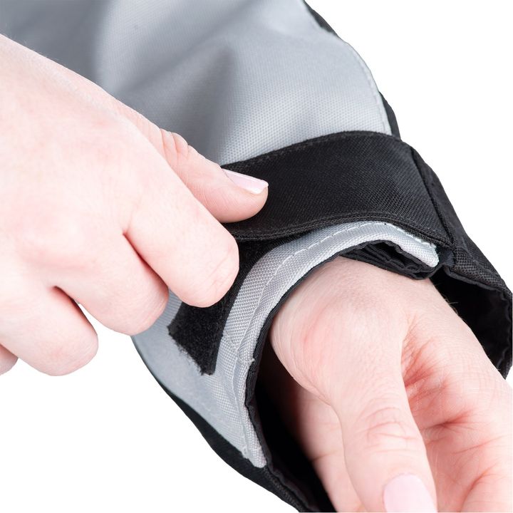 A close-up image of hands adjusting a black and gray fabric with hook and loop fastener, possibly a piece of clothing or sports equipment.