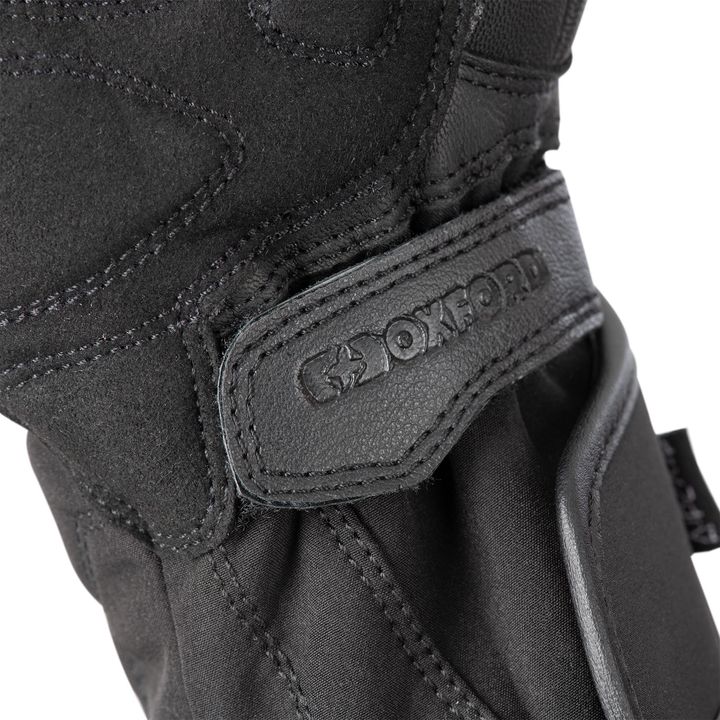 Close-up of a black textile motorcycle glove with a Velcro strap showing the embossed logo "OXFORD."