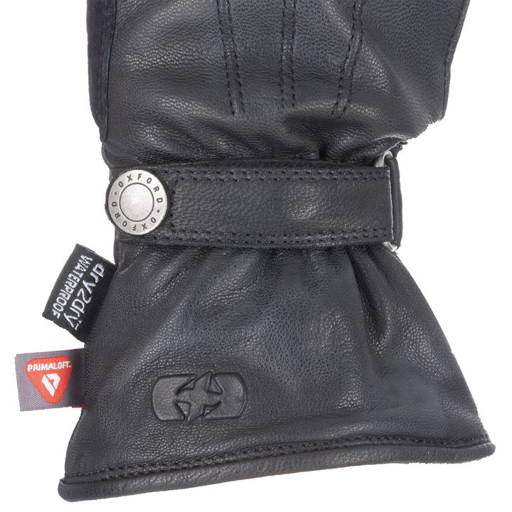 Close-up of a black leather motorcycle glove with a metal snap button, featuring branding logos "PRIMALOFT" and "Oxford."