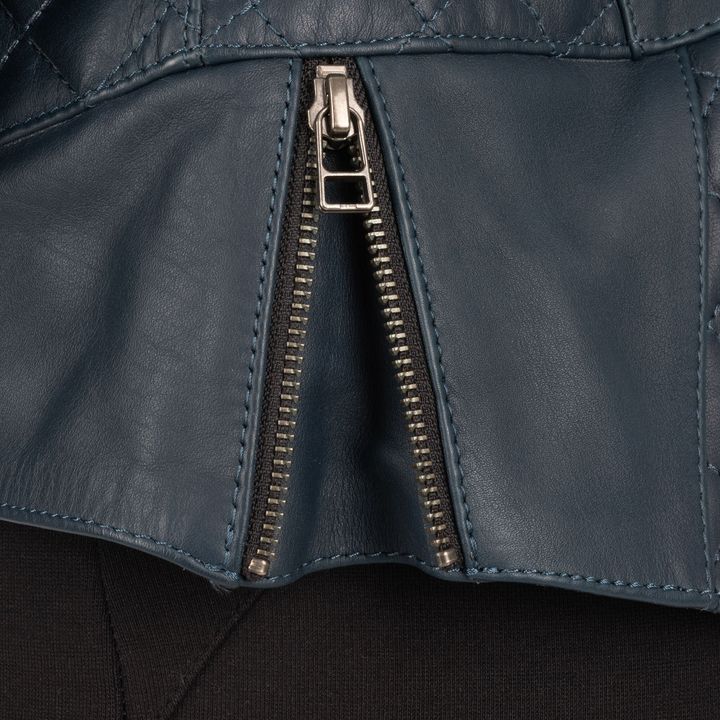 Close-up of a partially unzipped silver metal zipper on a navy blue leather garment with visible stitching details.