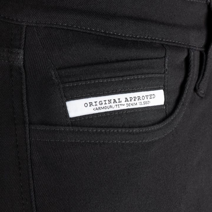 Close-up view of a black denim garment with a white label displaying the text "Original Approved Armourlite™ Denim 13.5oz".