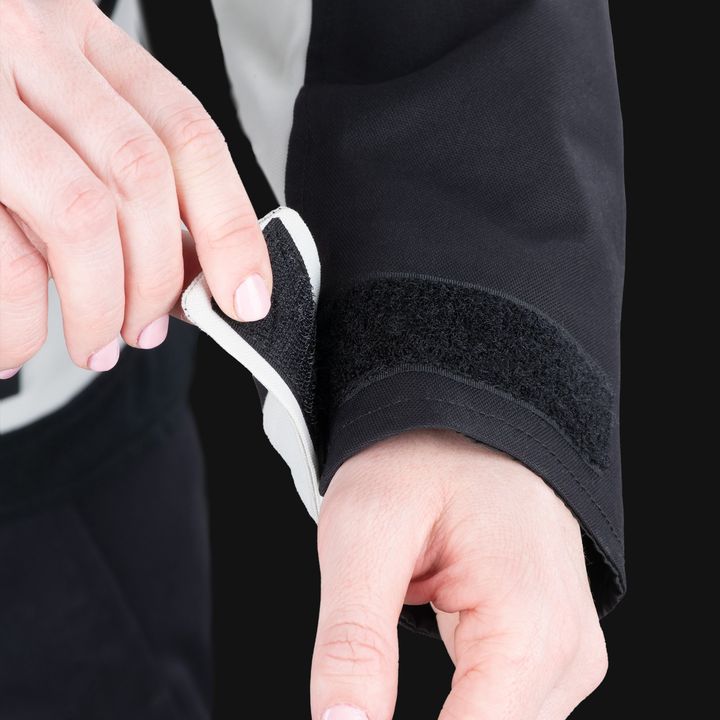 A person is adjusting a black neoprene elbow brace with Velcro straps on their right arm.