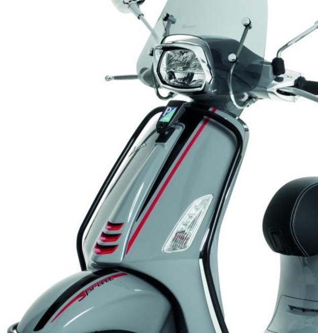 Vespa Front Side Protection Elettrica/Sprint/Primavera A close-up view of a silver scooter with red and black stripes detailing, featuring a clear windscreen, rounded headlight, and an ergonomic black seat.