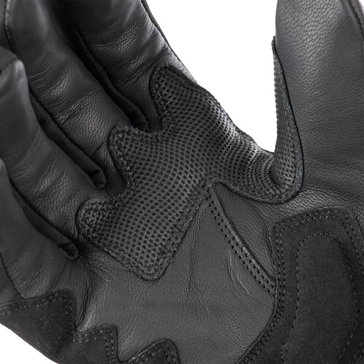 Close-up of a black motorcycle glove highlighting the textured grip material on the palm and the protective leather padding on the back of the hand.