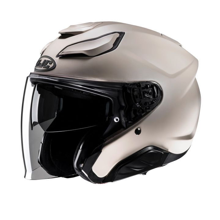 A modern full-face motorcycle helmet in a matte beige color, featuring a raised vent system on the top and a brand logo above the visor area.